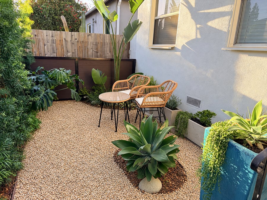 Unwind in your private garden patio with two outdoor chairs, bistro table, lush greenery, and low-maintenance landscaping. Ideal for morning coffee or evening relaxation.