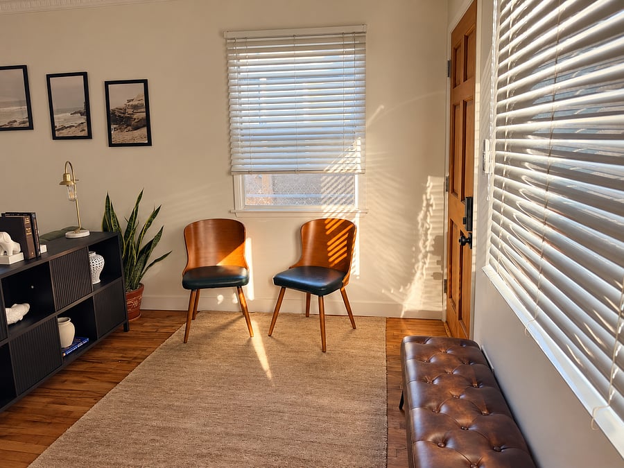Sun-filled seating area near the entrance with comfortable chairs, natural hardwood floors, and welcoming coastal-inspired decor.