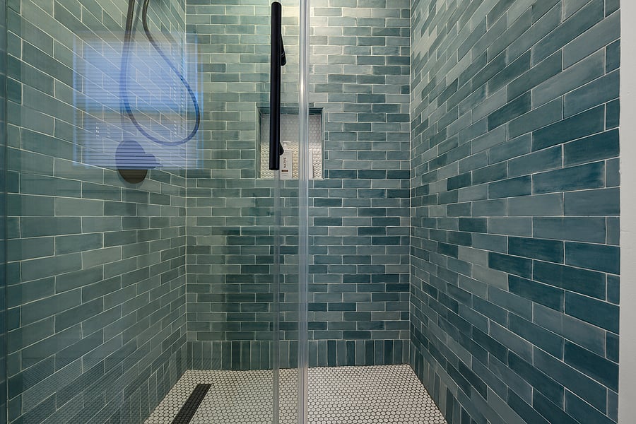 Newly remodeled bathroom with large standing shower, aqua blue subway tile, and modern fixtures.