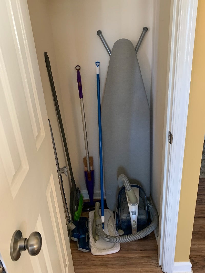 Nicely stocked closet with mops, vacuum, ironing board and supplies.