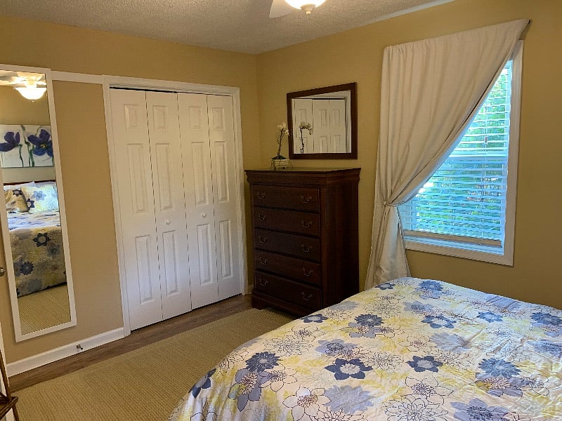 Extra tall mirror and double door closet with hangers provided on long rod and storage shelf above.