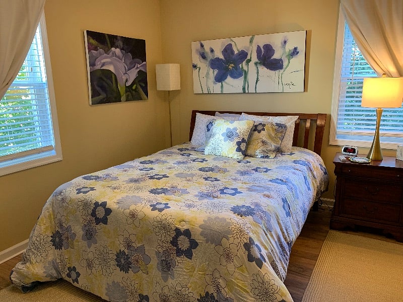Queen bed with floral theme. Room darkening drapes as well as wide slat blinds.