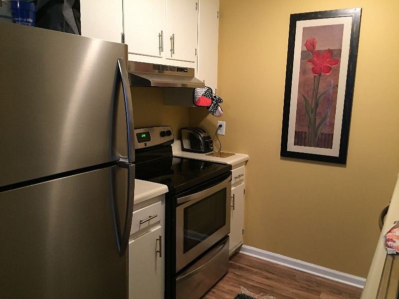 Kitchen with stainless fridge and glass top stove.
