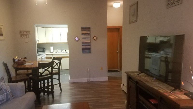 Living room showing dining area front entrance door, kitchen and large 42 in Smart/Roku TV