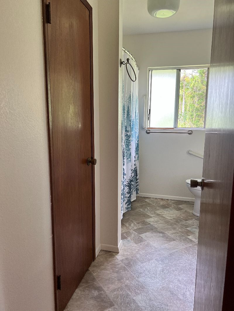 Main bathroom with tub/shower and large linen closet. There are handicap grab bars by commode and shower.