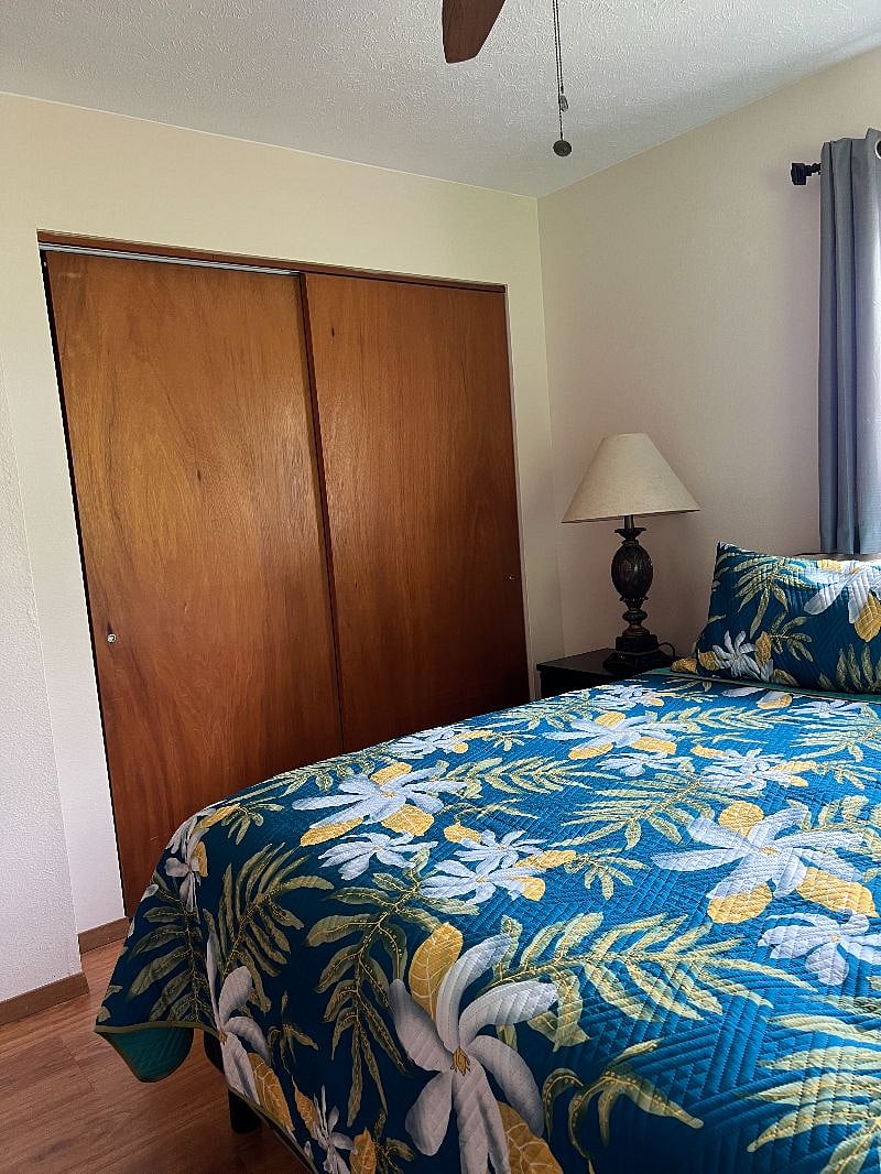 Third bedroom with large dresser, nightstand with lamp, large closet, chair, ceiling fan/light, new room darkening blinds and blackout drapes.