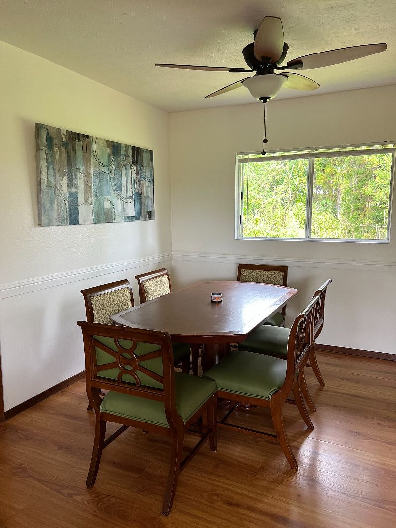 New dining room table with 6-chairs, window with view of jungle.
