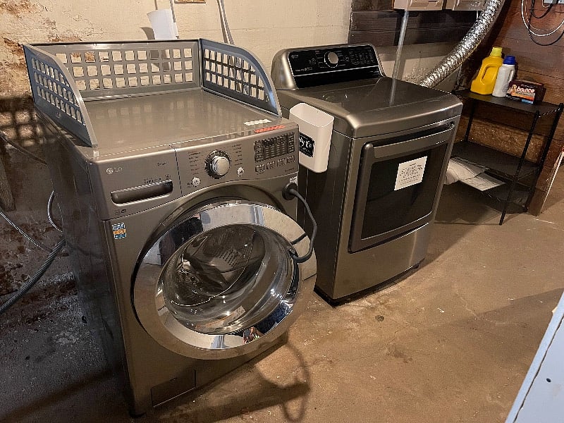 Shared washer and dryer for both apartment units located in the basement. Shelving next to dryer for detergent storage. 