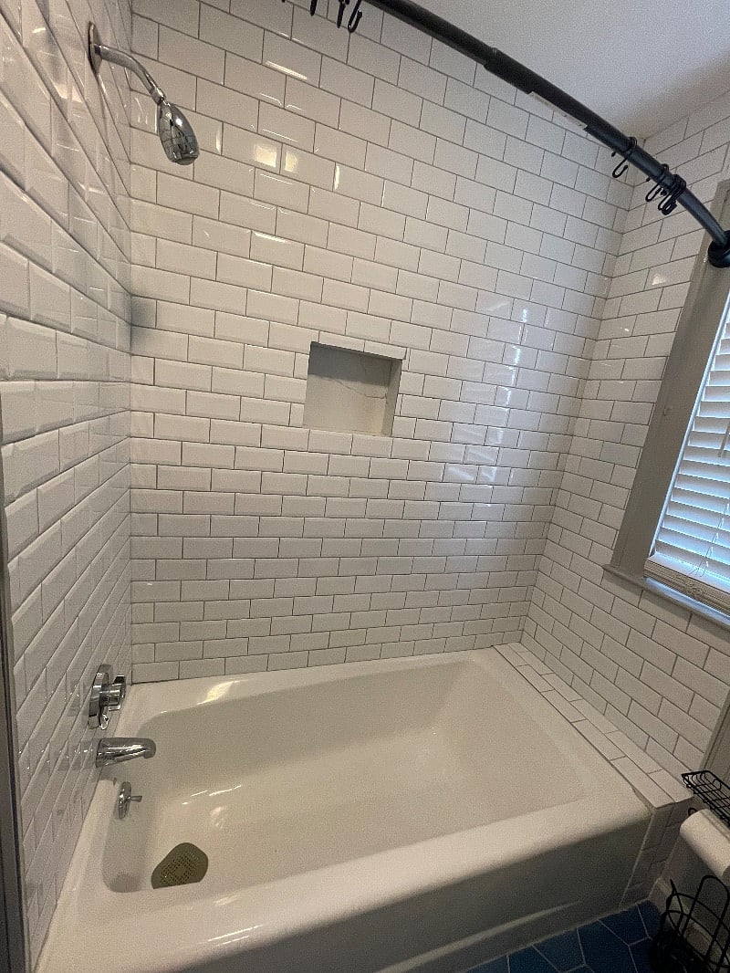 Beveled subway tiles shower with built-in storage for shower toiletries. 