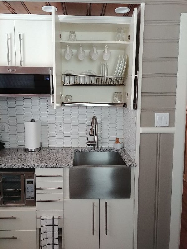 Kitchen detail. Dish drying rack is built in to cabinet over sink.