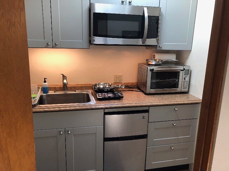 close up of kitchenette. 2 counter top induction burners, convection oven, microwave, fridge.