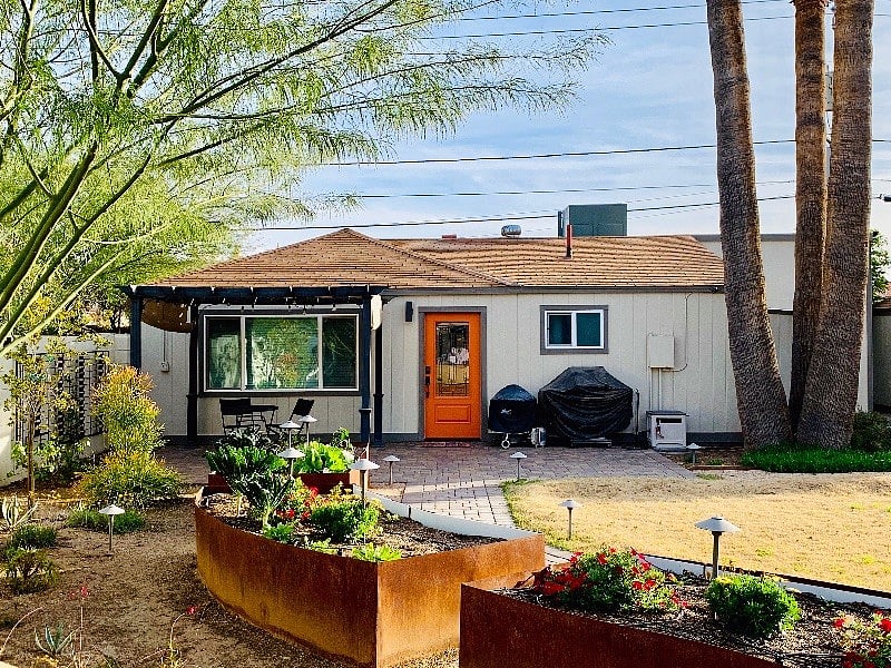 Inviting and charming guesthouse with desert landscaping, pergola, paver patio, grills, beautiful landscape lighting, and garden. 