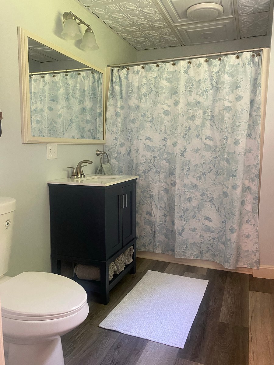 The bathroom has a shower/tub and a new vanity, toilet, flooring, mirror, lighting, paint and trim.