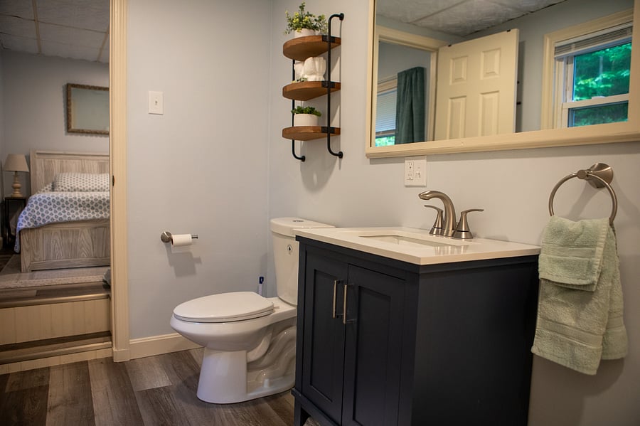 The bathroom has a shower/tub and a new vanity, toilet, flooring, mirror, lighting, paint and trim.