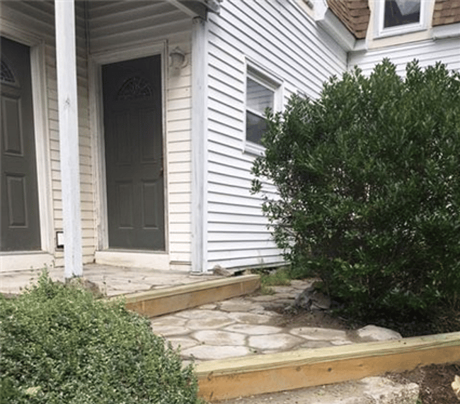 The apartment is on the ground floor in the back part of the house. There are stairs up to the apartment from the road and a few steps to the apartment itself (seen here).