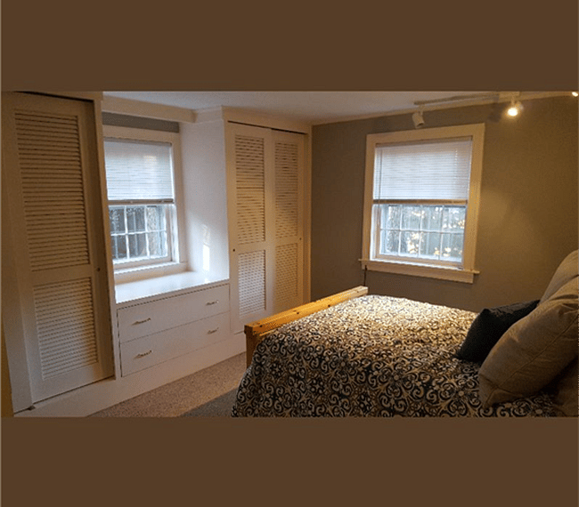 Bedroom with two windows with views to the private garden/pation, and a Queen sized bed.