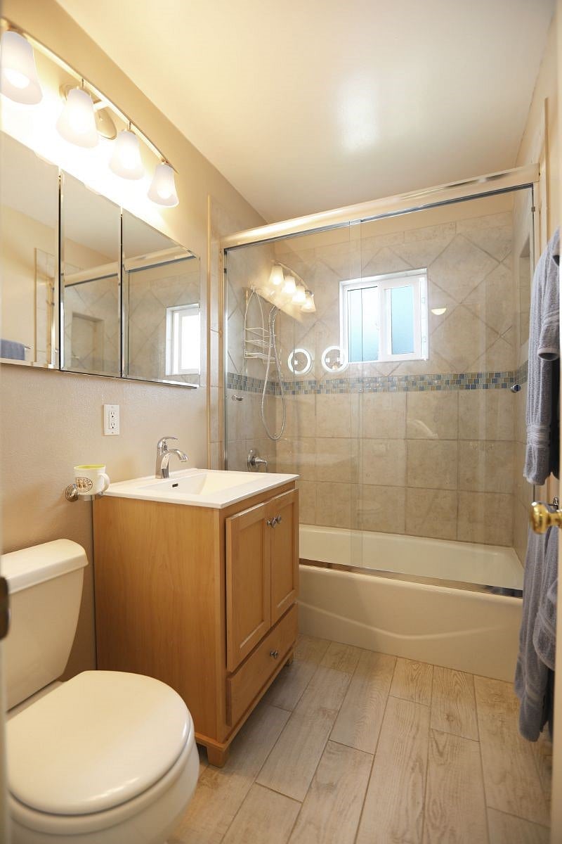 Bathroom with custom tile, wall of mirror storage, oversize glass shower doors.