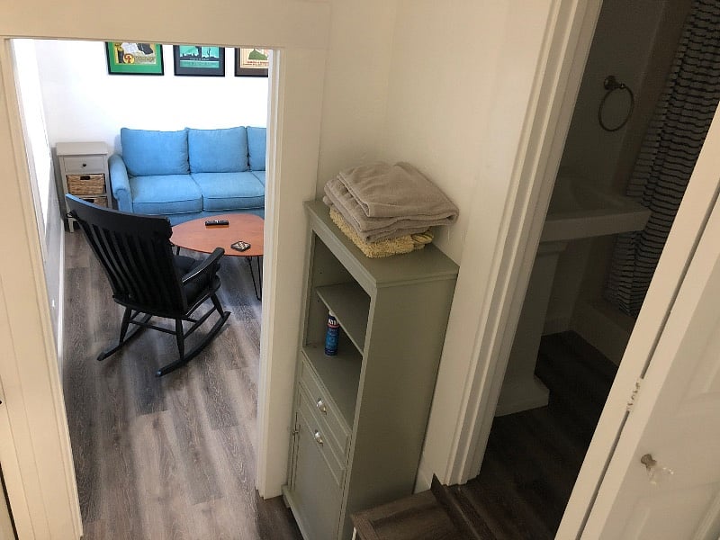 View from kitchen with bathroom on the right and living room in front of you with the bedroom area to the right of couch area