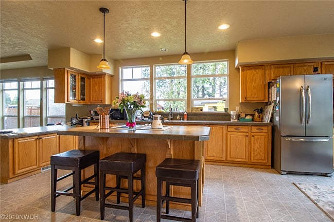 Large kitchen has eating bar with adequate cooking and kitchenware