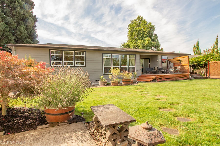 Back yard of home with walkway and deck leading to entry into Harmony Unit 2