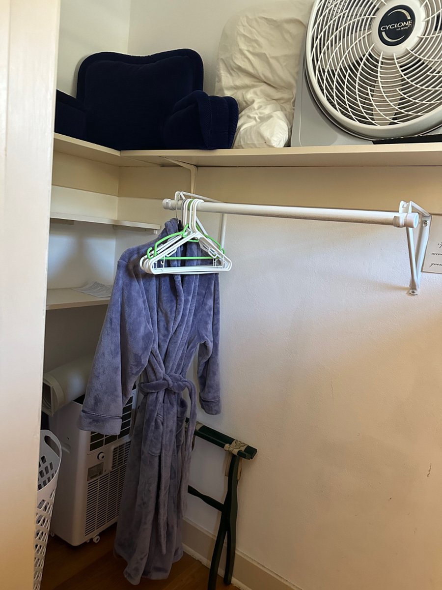 Roomy closet in the bedroom with robe, yoga mat, luggage rack, TV tray, bolster, extra pillow, and portable AC unit.