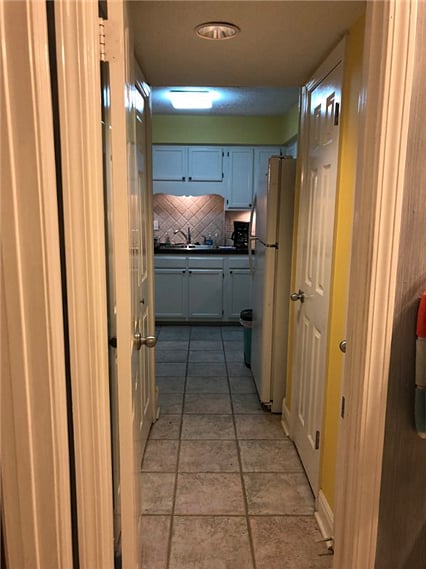 Walk way to kitchen from downstairs bathroom  with Laundry closet to the left and pantry and  a storage closet to the right.