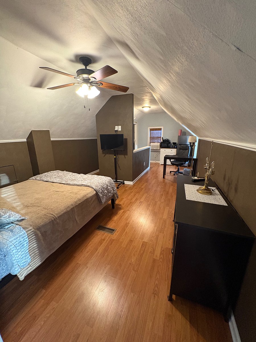 Queen Bed with small desk in front of kitchette with small fridge, microwave and small coffee pot.
