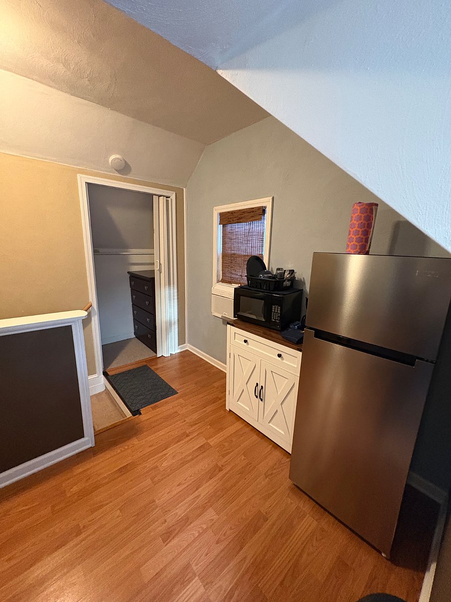 Kitchenette with small fridge, microwave, coffee maker. Closet and small dresser in the background.