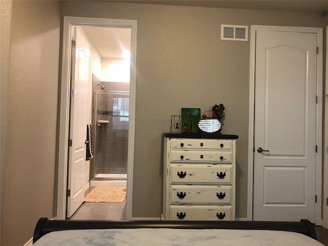 Dresser in master bedroom, door open to full bath, door closed to laundry room