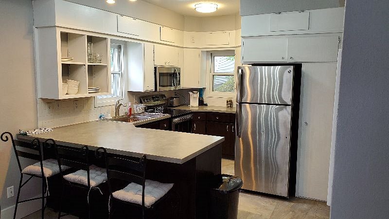 The kitchen includes a full-size fridge, range, microwave, dishwasher, disposal, along with pots/pans, coffee pot, slow cooker, toaster, and plenty of dinnerware and silverware.