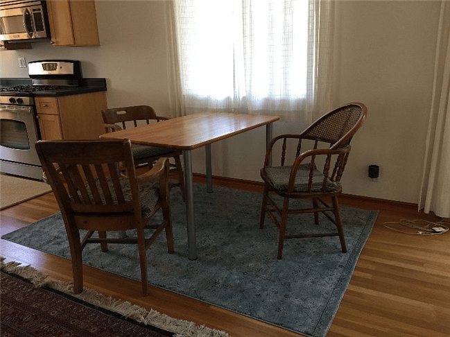 Dining Area table next to kitchen with seating for three persons. Wooden table with metal legs and 3 comfortable wooden chairs