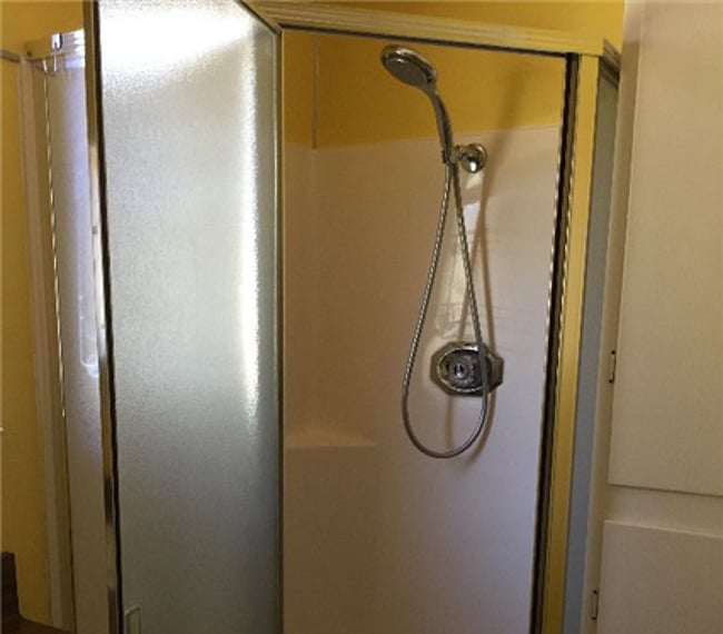 Shower cabinet with removable shower head. Hot water is supplied from a 50-gallon tank on the owner's side