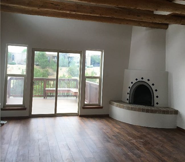 Living room with kiva fireplace, vigas, abundant light & outdoor deck