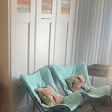 murphy bed in wall with 2 plush teal color chairs 
