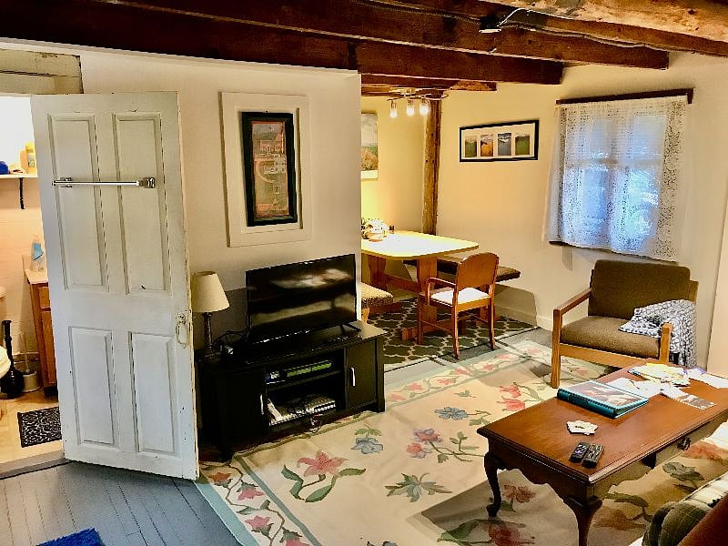 The table, benches, chair in the eating/study area off the living room is also great for craft projects and for use as a large desk. There is ample track lighting above it. The bathroom is through the door at left.