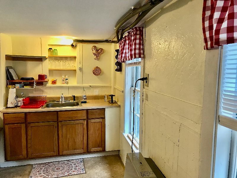 This photo is taken from the hallway into the living room, looking back into the west side of the kitchen There are storm/screens or double-glazing on all the windows in the cottage.