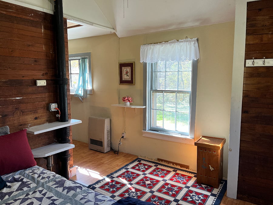This is the west wall of the bedroom and the hall back toward the bathroom and then the living room and kitchen. The cottage has a rustic quality (given its architecture and building date) and cozy spaces.