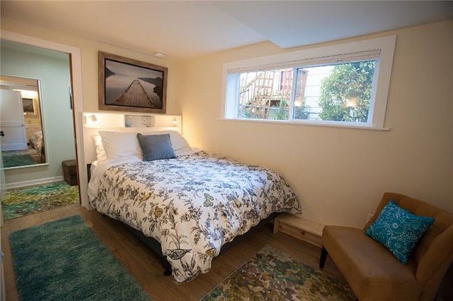 Queen bed with electronics charging station and reading lights in built-in headboard; large window for fresh air and garden views