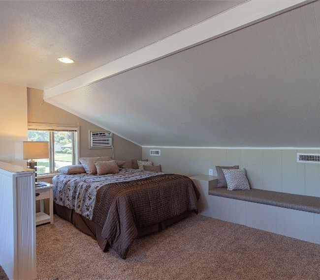 Your comfortable queen bed next to padded bench