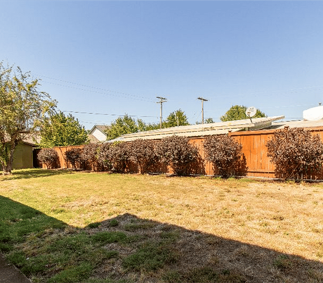 Large fenced, private backyard with covered patio and seating area