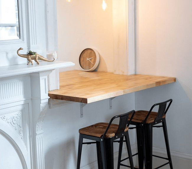 Dining passthrough with modern barstools and edison bulb lighting, original decorative fireplace with mirror.