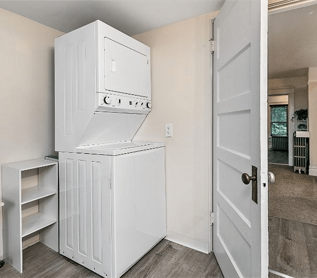 Laundry area. Washer and Dryer. View from the end of the bathtub showing perspective through the living room and the kitchen to the front of the apartment.