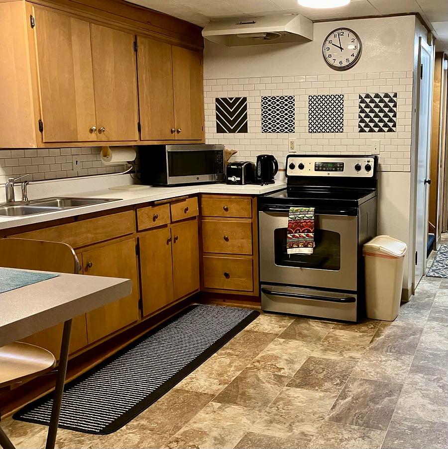Kitchen is equipped with glass-top electric range, full-size refrigerator/freezer, portable dishwasher, microwave, toaster, electric kettle, coffeemaker, and counter seating.