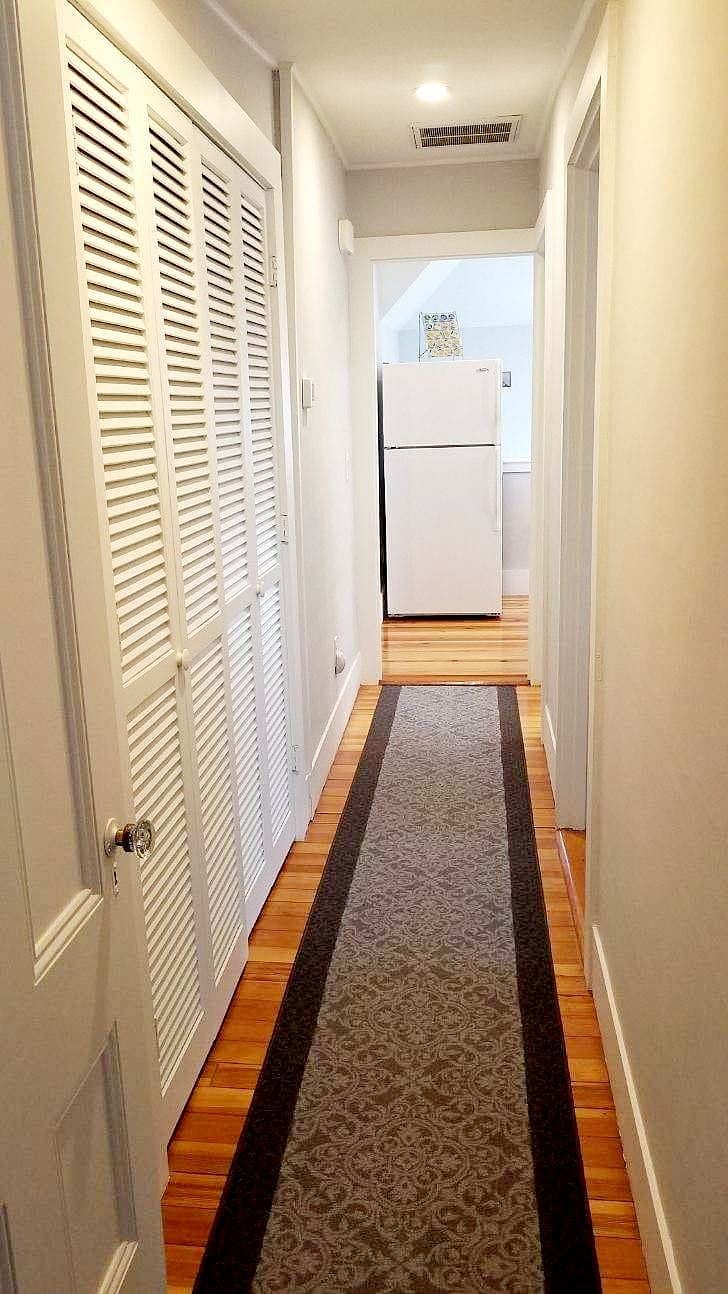 View of hall to bedrooms (facing the kitchen). Doors to the left open to a large additional storage area off of the hall.