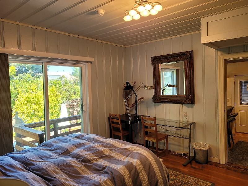 view from bedroom, including sliding door to deck and view of garden