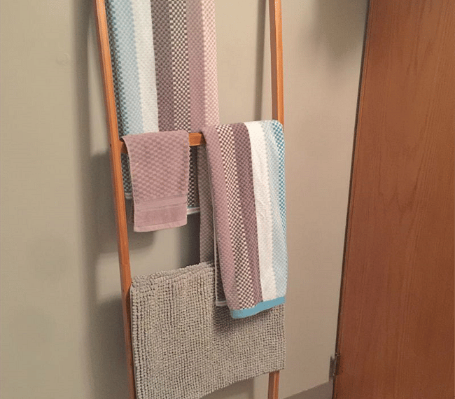 Bathroom towel rack is tucked behind the door next to the shower.
