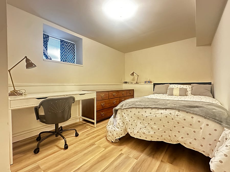 Bedroom with full size bed, closet, desk, dresser, and built-in shelving and natural light.