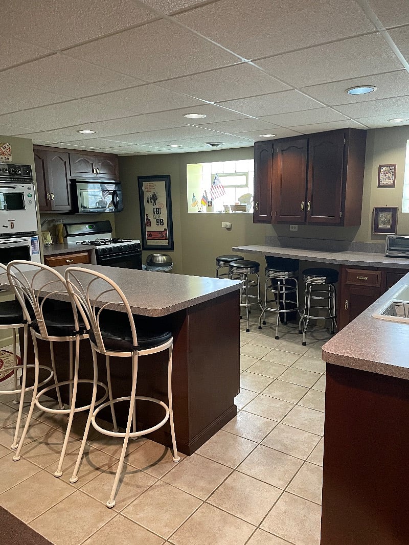 Island looking into a large kitchen with a double oven, dishwasher and microwave.