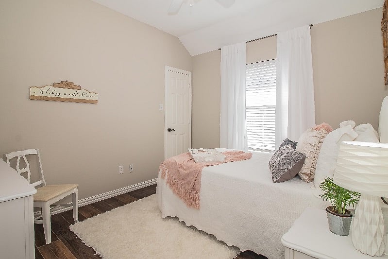 View of bedroom showing entrance to walk-in closet with full-length mirror, luggage rack, and laundry hamper.