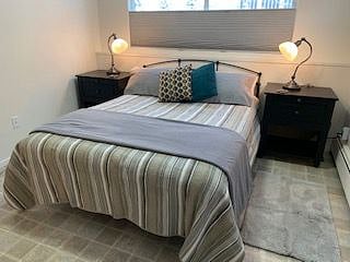 Bedroom with queen bed and reading lamps.